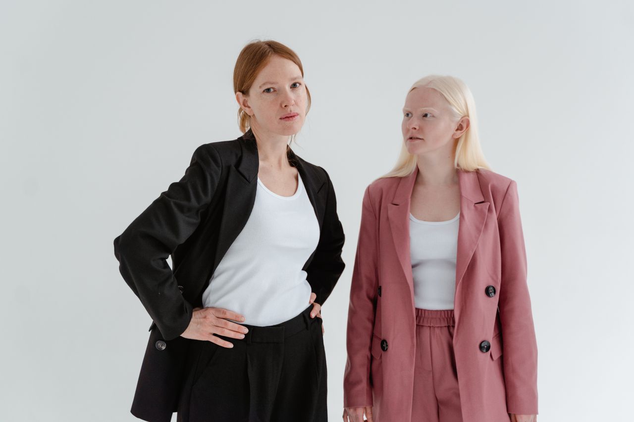 services-04 Two women in business suits exuding confidence on a white studio background.